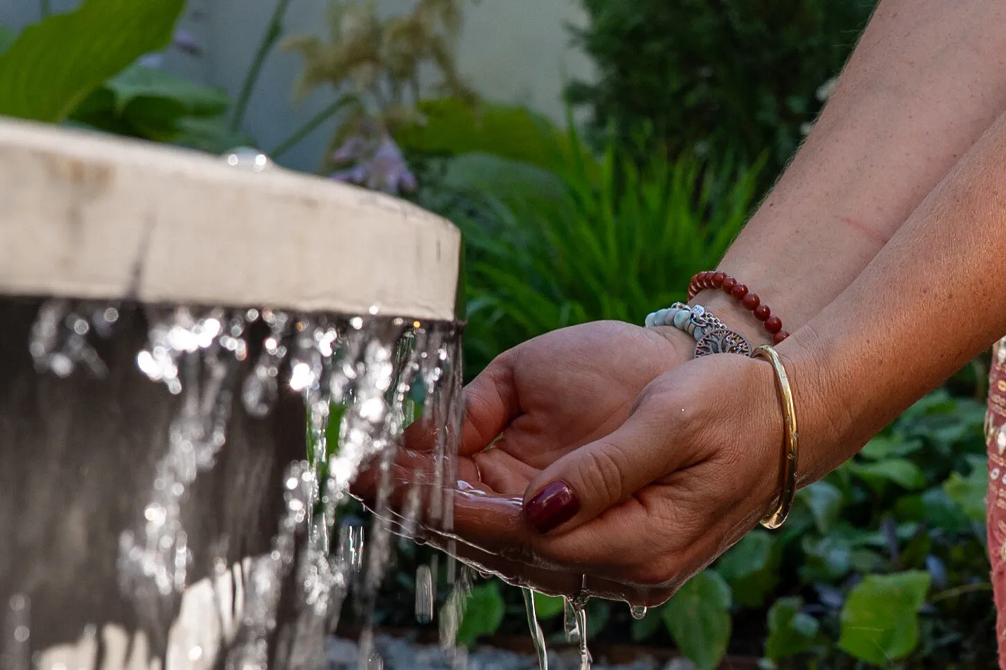 Hands touching flowing water in a sensory wellbeing garden designed to encourage connection with nature