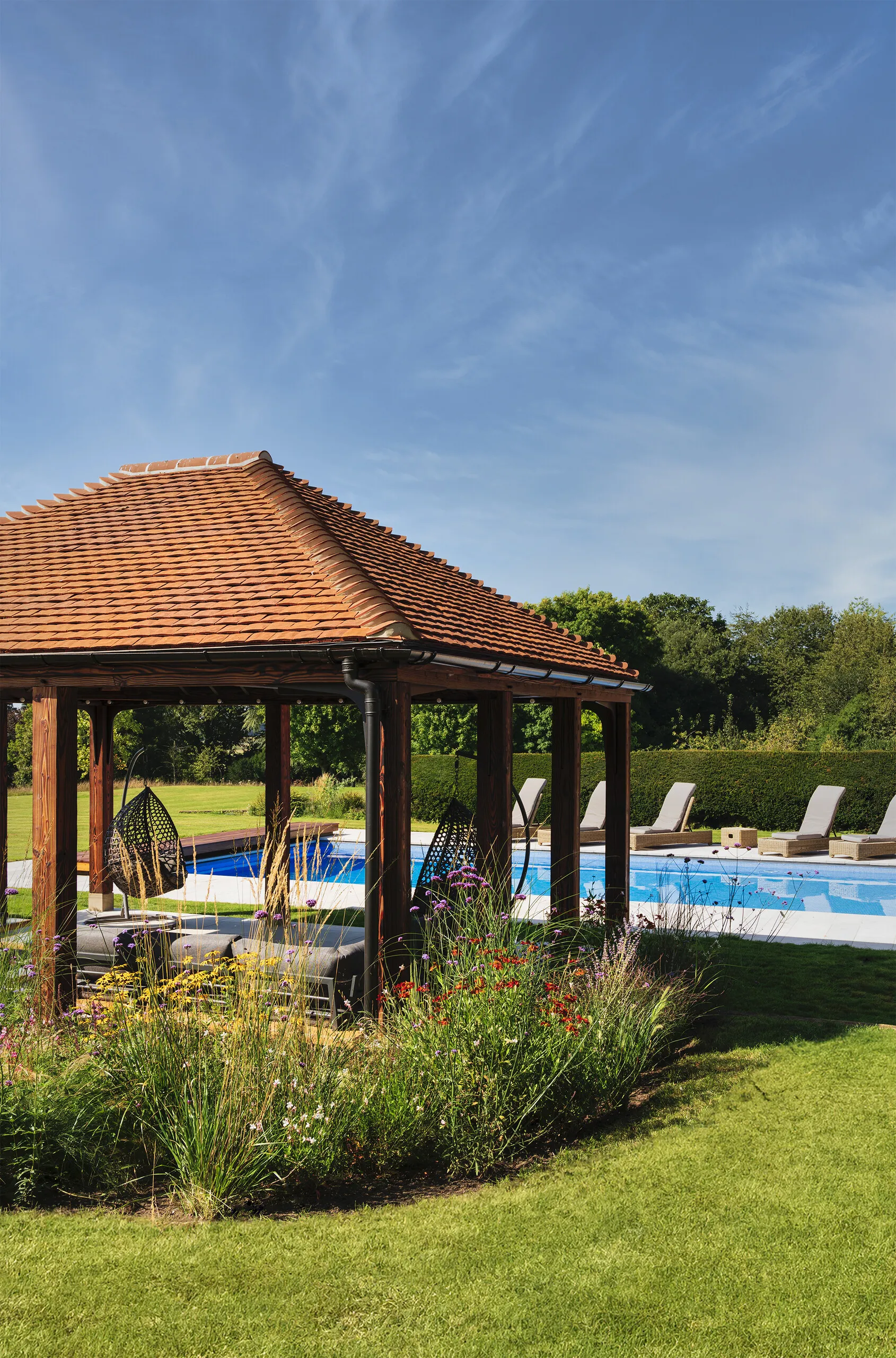 Luxury garden with swimming pool, timber pavilion and colourful naturalistic planting designed for outdoor living and wellbeing
