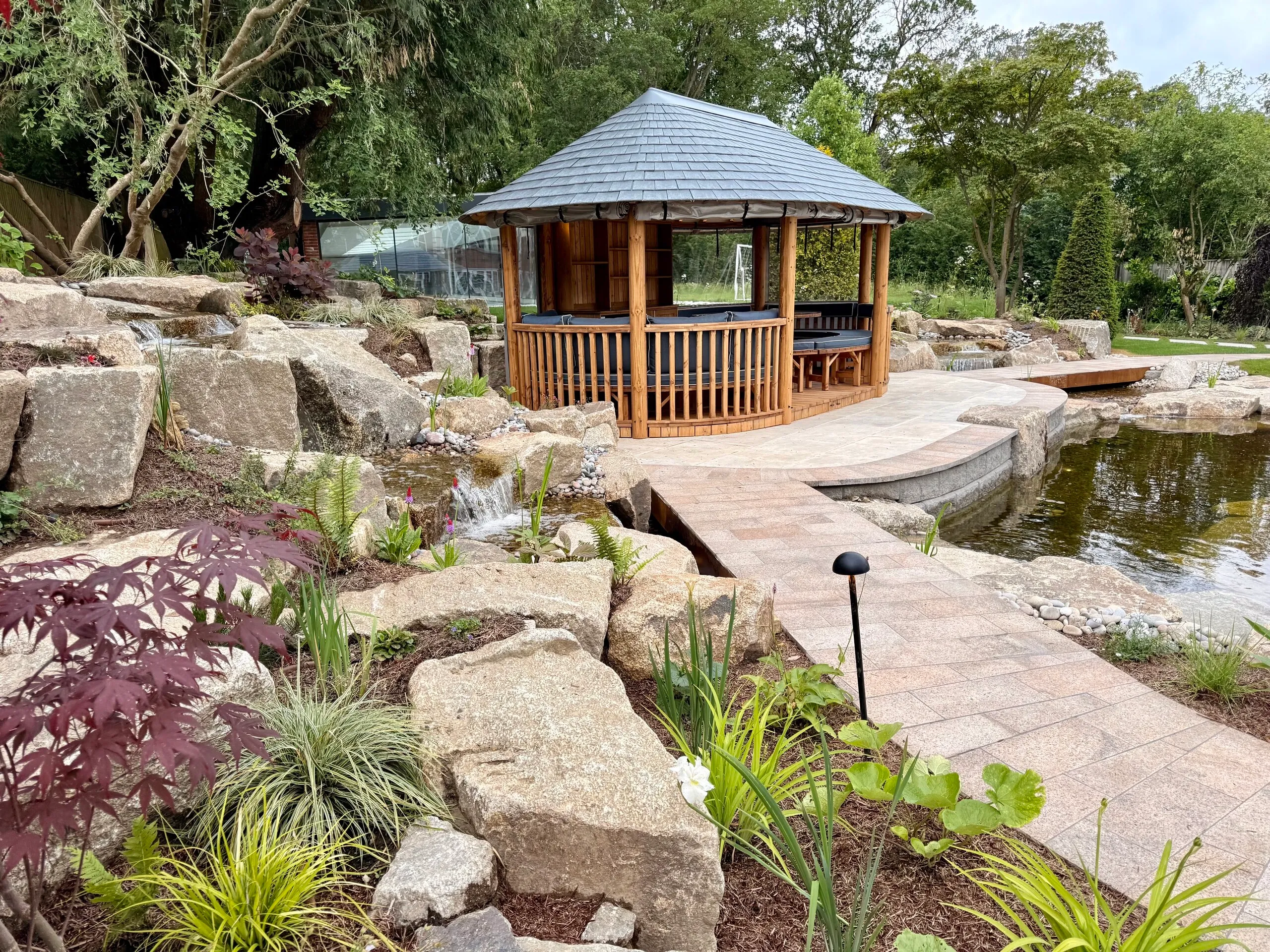 Water and wellbeing garden with natural waterfalls, ponds, granite boulders and a Breeze House designed by Kitti Kovacs Garden Design